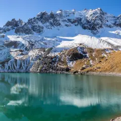 Lac d'altitude aux eaux turquoise, reflets des montagnes enneigées. Idéal pour une randonnée à Ceillac par temps ensoleillé.