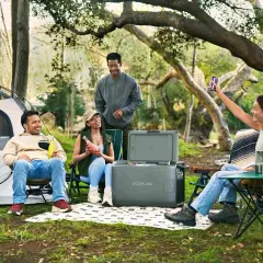 Amis profitant d'un emplacement camping-car chez particulier, avec tente, glacière et boissons.