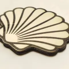 Coquille de bois stylisée, rappelant la coquille Compostelle, avec des lignes noires sur fond clair.