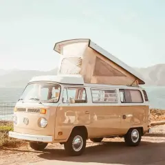 Un camping-car Volkswagen vintage, prêt pour l'aventure, avec son toit relevé, face à la mer et aux collines. L'esprit des 5 Terres en camping-car.