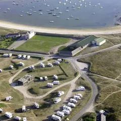 Vue aérienne d'une aire de camping-car finistère gratuit, avec des caravanes garées près d'une baie bordée de bateaux.