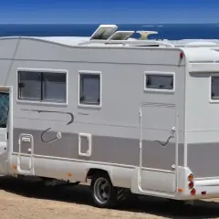 Camping-car blanc stationné sur une aire de camping-car à Bormes-les-Mimosas, face à la mer Méditerranée.