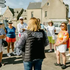 Un groupe de touristes écoute attentivement une guide dans le Val de Saire, un lieu unique par nature.