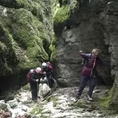 Trois randonneurs explorent le canyon des Gueulards, un passage étroit et rocheux couvert de mousse.