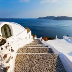 Escalier en pierre menant à la mer bleue, typique des Cyclades. Maisons blanches perchées sur la falaise.