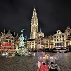 Deux souris en peluche posent devant la cathédrale d'Anvers illuminée la nuit, un moment parfait pour visiter Anvers.