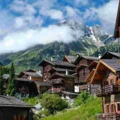 Villages de chalets en bois fleuris, montagnes enneigées en arrière-plan. Une belle idée de que faire en Suisse pour un séjour pittoresque.