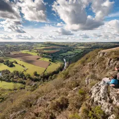 Vue panoramique de la Suisse Normande, une carte vivante de collines verdoyantes, d'une rivière sinueuse et d'un père et son enfant contemplant le paysage.