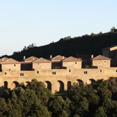 Vue d'une chartreuse en pierre, perchée sur une colline boisée, parfaite pour une randonnée Chartreuse de la Verne.