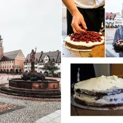 Un pâtissier présente une Forêt Noire en Allemagne, une ville pittoresque avec une fontaine et des maisons traditionnelles.