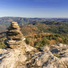 Un cairn marque le chemin de Stevenson, offrant une vue imprenable sur les collines automnales. Chaque étape est une découverte.