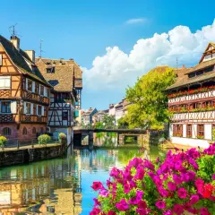 La Petite France à Strasbourg, un joyau pour l'alsace tourisme. Maisons à colombages pittoresques au bord de l'eau, reflets dans le canal, fleurs éclatantes.