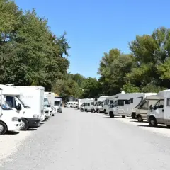 Grand parking de camping-cars près du zoo de Beauval, sous un ciel bleu et des arbres verdoyants.
