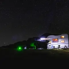 Un camping-car et un 4x4 illuminés sous un ciel étoilé. L'endroit parfait où dormir en camping-car pour admirer la voie lactée.