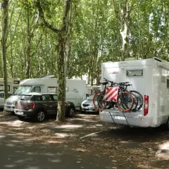 Stationnement gratuit pour camping-cars à Bordeaux, sous les arbres. Des vélos sont prêts pour explorer la ville.
