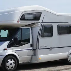 Camping car Hymer sur le bord du canal de Nantes à Brest, au milieu d'un champ de colza en fleurs.