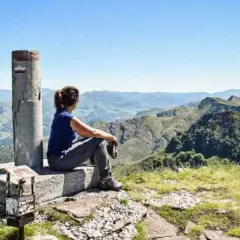 Vue panoramique sur les montagnes verdoyantes du gr pays basque. Une randonneuse contemple le paysage depuis un sommet.