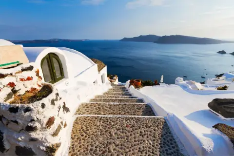 Escalier en pierre menant à la mer bleue, typique des Cyclades. Maisons blanches perchées sur la falaise.