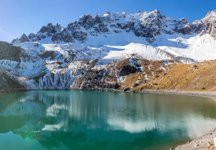 Lac d'altitude aux eaux turquoise, reflets des montagnes enneigées. Idéal pour une randonnée à Ceillac par temps ensoleillé.