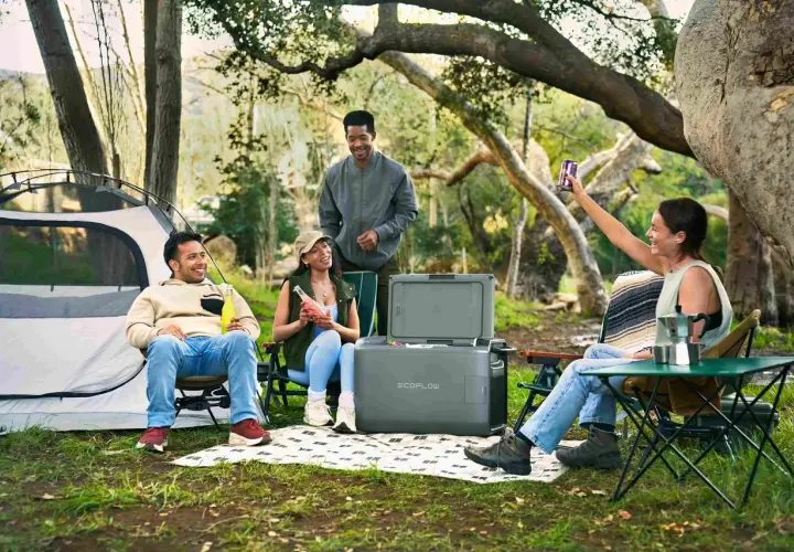 Amis profitant d'un emplacement camping-car chez particulier, avec tente, glacière et boissons.