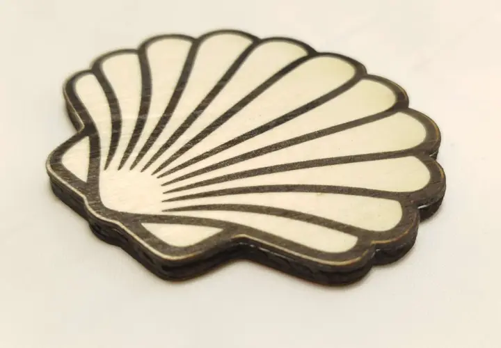 Coquille de bois stylisée, rappelant la coquille Compostelle, avec des lignes noires sur fond clair.