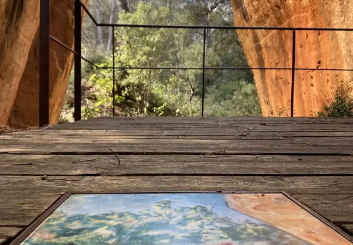 Sur le plateau de Bibemus, un tableau posé sur un pont de bois offre une vue sur la nature environnante, dominée par des falaises ocres.