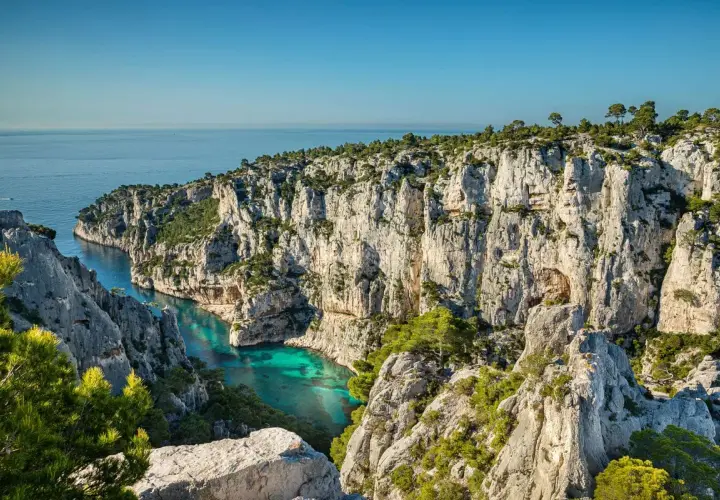 Vue spectaculaire depuis le belvédère d'En Vau sur la calanque aux eaux turquoise, entourée de falaises calcaires et de pins.
