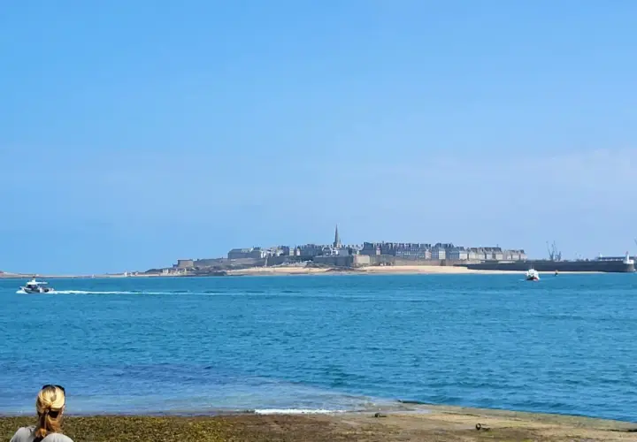 Une personne admire la vue sur la ville fortifiée, une belle journée pour une randonnée le long de la Rance.