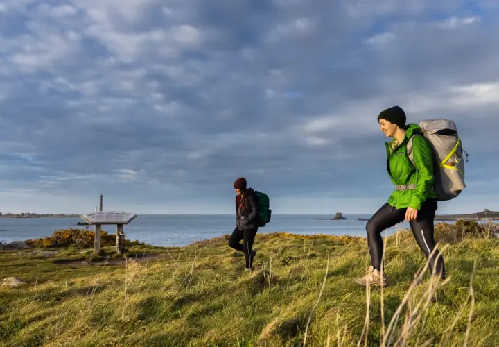 Deux randonneuses explorent le littoral breton, profitant d'une belle journée pour leur randonnée les abers Bretagne. Le ciel est couvert, mais la lumière est douce.