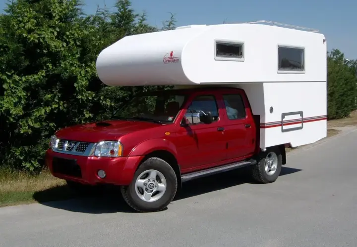 Un camping-car increvable rouge, prêt pour l'aventure. Sa cabine blanche offre un espace de vie confortable pour explorer le monde.