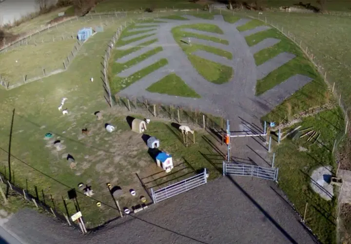Vue aérienne de la ferme de Bihen avec des animaux, des abris et des emplacements de camping aménagés.