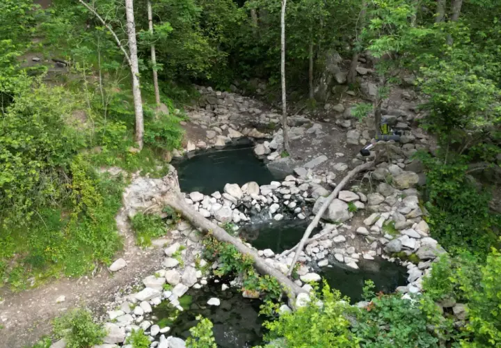 Baignades naturelles dans la forêt, près de Merens-les-Vals. Un sac à dos est posé sur un tronc d'arbre.