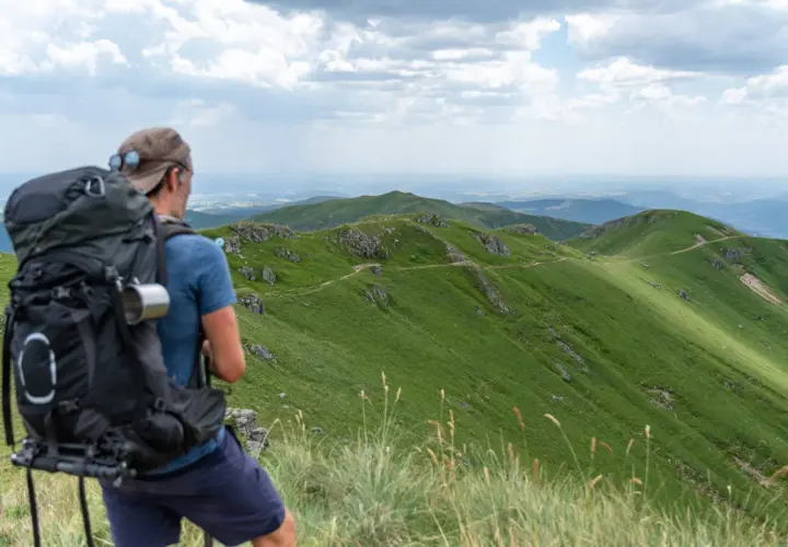 Randonnée Cantal 2 jours : un randonneur admire le paysage verdoyant des monts du Cantal, prêt pour son aventure.