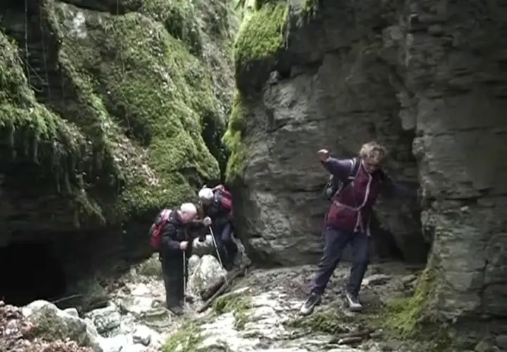 Trois randonneurs explorent le canyon des Gueulards, un passage étroit et rocheux couvert de mousse.