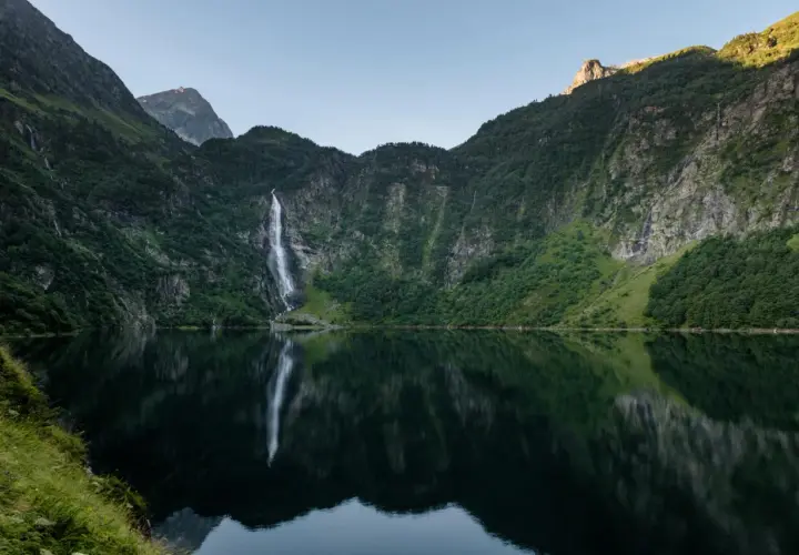 Le lac d'Oo, miroir des montagnes verdoyantes et de sa cascade majestueuse, offre un spectacle paisible.