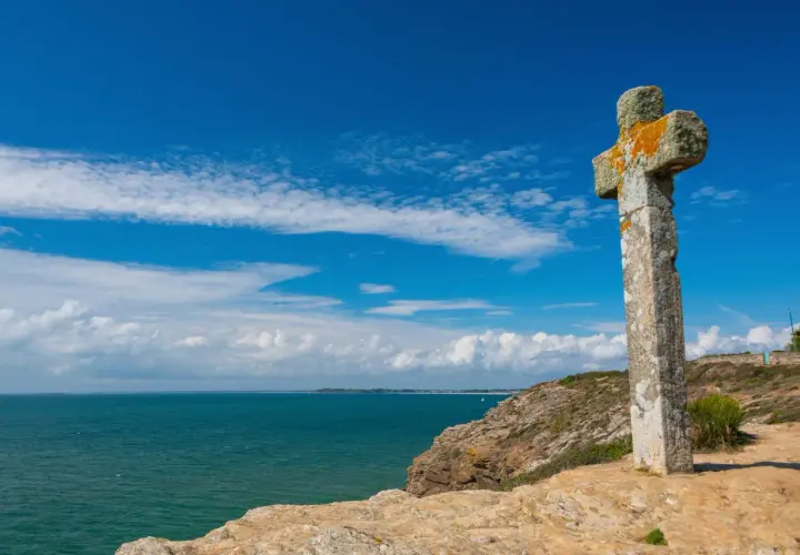 Croix de pierre patinée par le temps, dominant la mer d'un bleu profond. Une belle balade sur la presqu'île de Rhuys.
