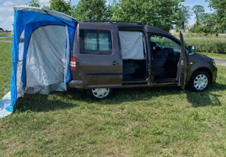 Un caddy tramper aménagé avec une tente latérale bleue et grise, prêt pour l'aventure en plein air.