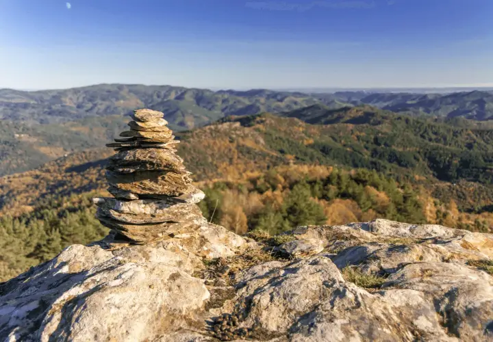 Un cairn marque le chemin de Stevenson, offrant une vue imprenable sur les collines automnales. Chaque étape est une découverte.