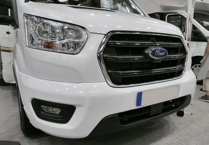 Avant d'un camping-car blanc avec le logo Ford. Ce véhicule est équipé d'un moteur Ford 2.2 TDCI, parfait pour vos voyages.