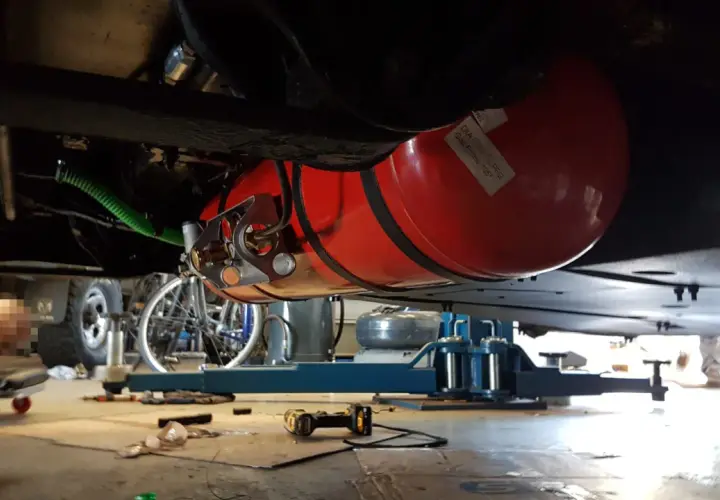 Installation d'un réservoir GPL sous un camping-car, respectant la réglementation GPL camping-car. Le réservoir rouge est visible, fixé sous le châssis.