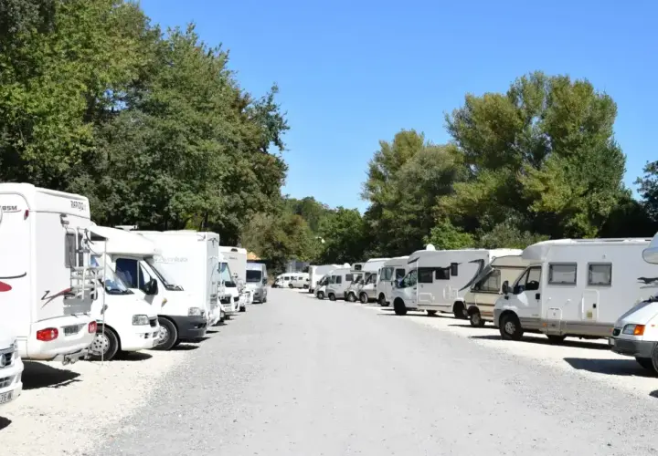 Grand parking de camping-cars près du zoo de Beauval, sous un ciel bleu et des arbres verdoyants.
