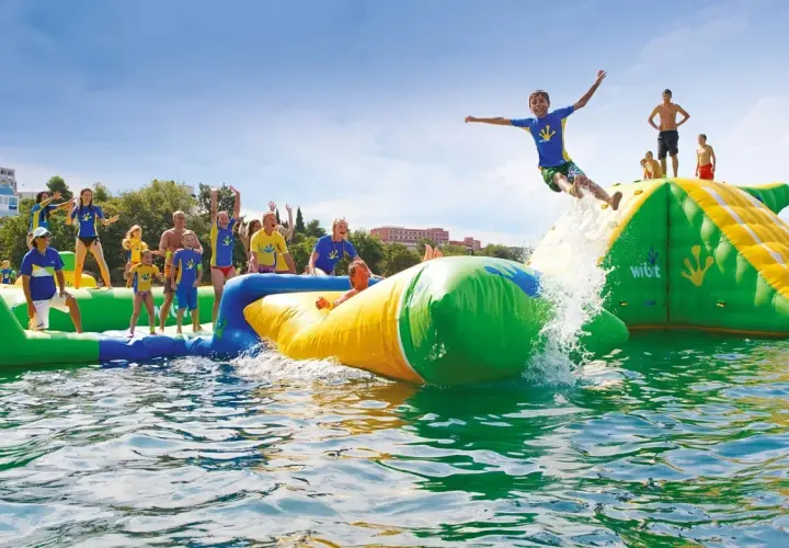 Des enfants s'amusent dans un aquapark gonflable près de Paris, un garçon saute dans l'eau.
