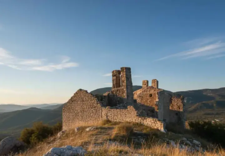 Ruines d'un château médiéval à Châteauneuf-les-Moustiers, baignées par la lumière dorée du soleil couchant, dominant un paysage de collines verdoyantes.