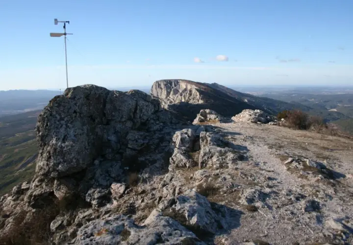 Sommet rocheux avec un anémomètre, offrant une vue panoramique sur la vallée. Le pic des mouches altitude est un lieu idéal pour observer le vent.