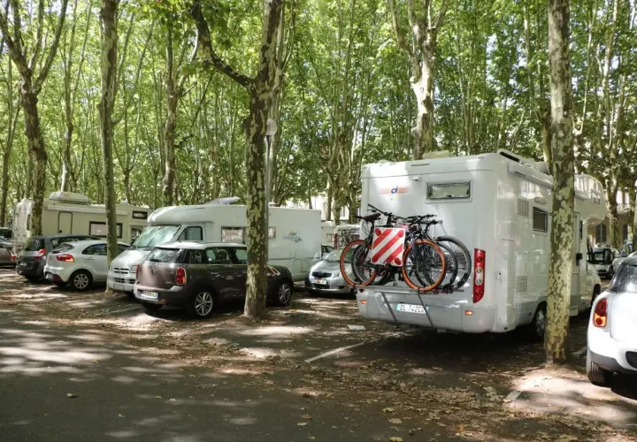Stationnement gratuit pour camping-cars à Bordeaux, sous les arbres. Des vélos sont prêts pour explorer la ville.