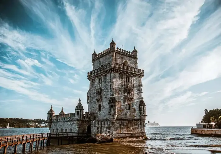La Tour de Belém, un incontournable pour savoir que faire à Lisbonne, se dresse fièrement sur l'eau sous un ciel spectaculaire.