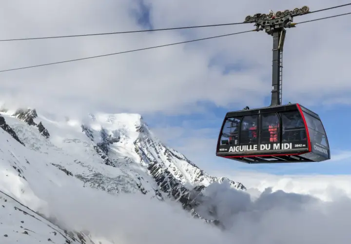 La télécabine de l'Aiguille du Midi survole un paysage alpin spectaculaire, transportant des passagers vers les sommets enneigés.