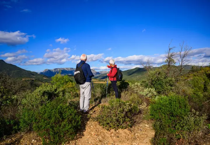 Un couple profite d'un week-end randonnée en amoureux, admirant le paysage montagneux sous un ciel bleu éclatant.