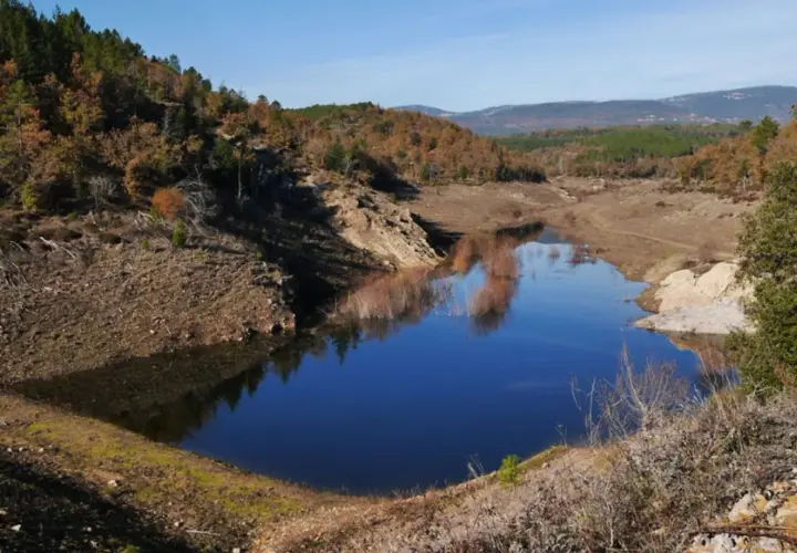 Le lac de Meaulx, aux reflets bleus intenses, est entouré de collines boisées aux couleurs d'automne.