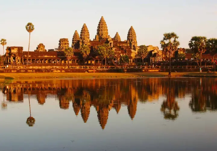 Angkor Wat au coucher du soleil, un incontournable pour savoir que faire au Cambodge. Les tours se reflètent dans l'eau.